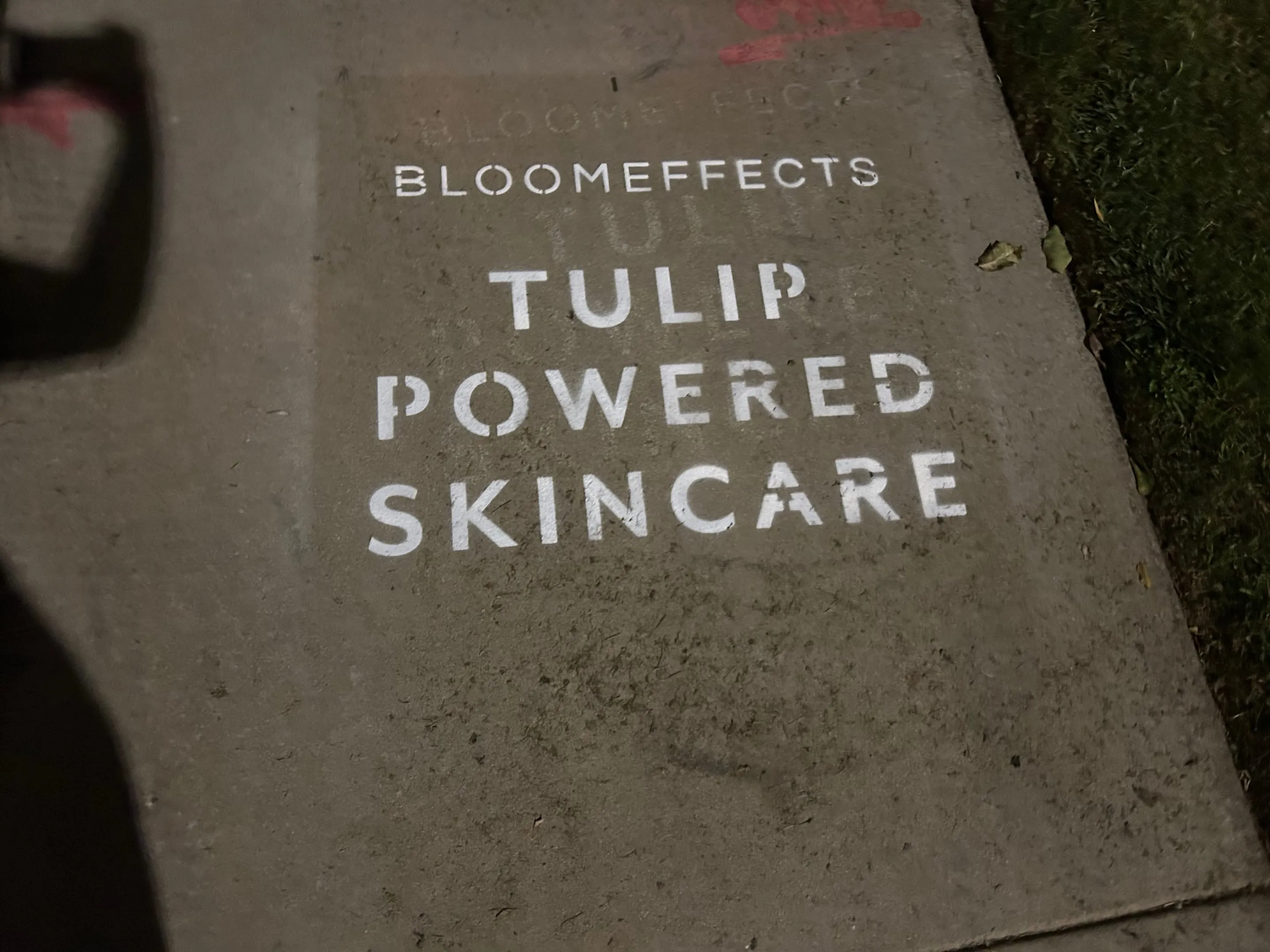 Sidewalk stencil install for Bloomeffects 'Tulip Powered Skincare' on New York City sidewalk in New York City - white stencil with tulip flower mark on concrete by Beyond Street Media