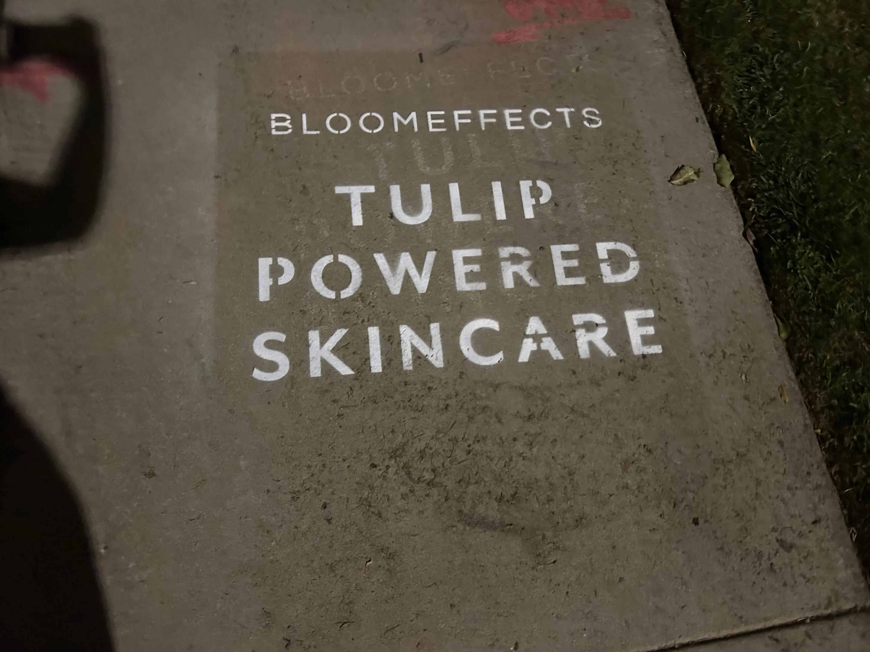 Sidewalk stencil install for Bloomeffects 'Tulip Powered Skincare' on New York City sidewalk in New York City - white stencil with tulip flower mark on concrete by Beyond Street Media