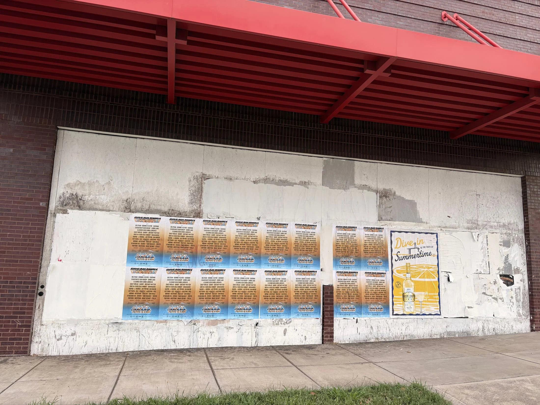 Full-color wheatpaste poster run for Breakaway Music Festival on a warehouse wall, E 11th St, Uptown Charlotte