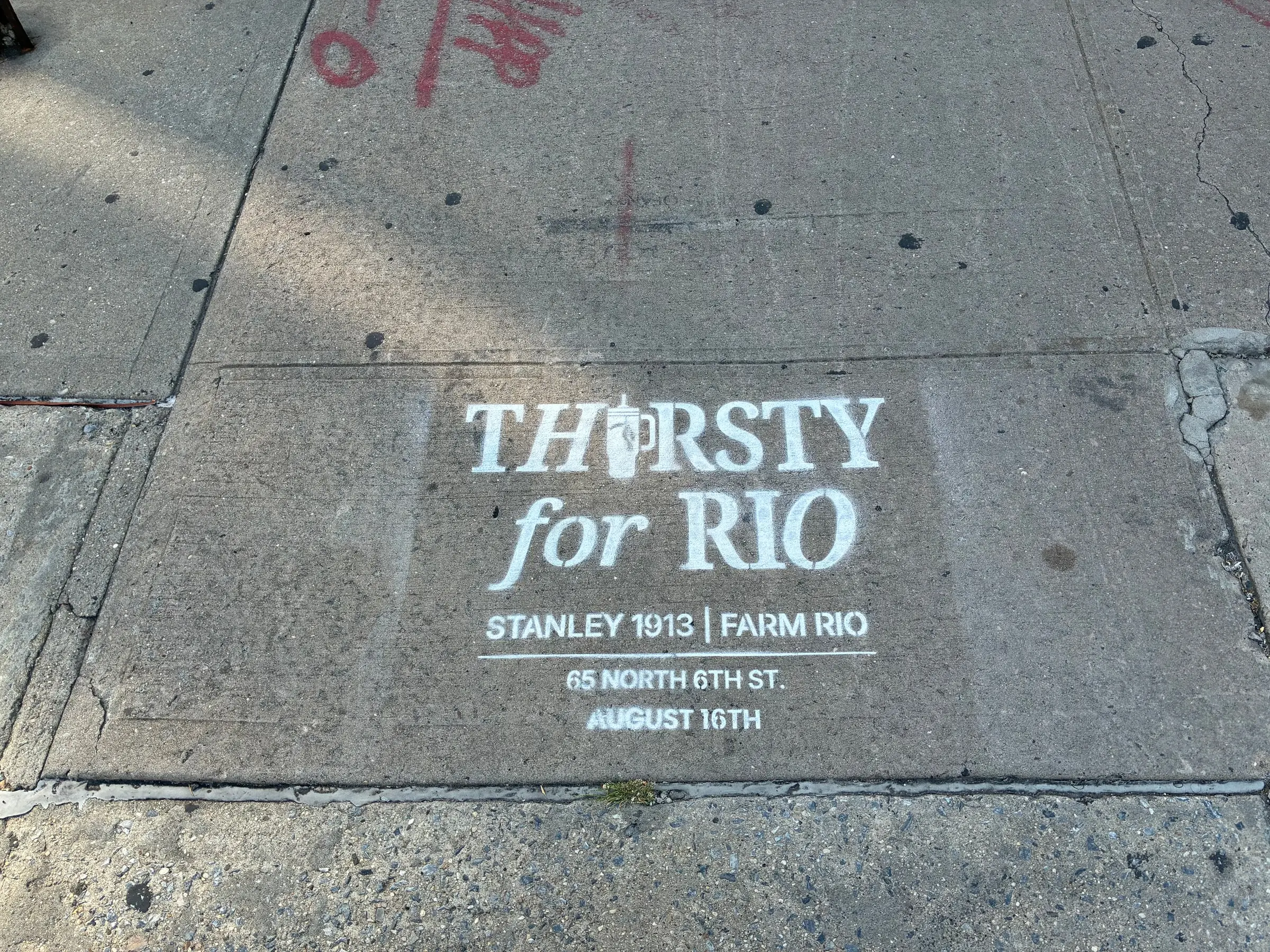Stencil on a weathered Williamsburg slab with red utility markings alongside.