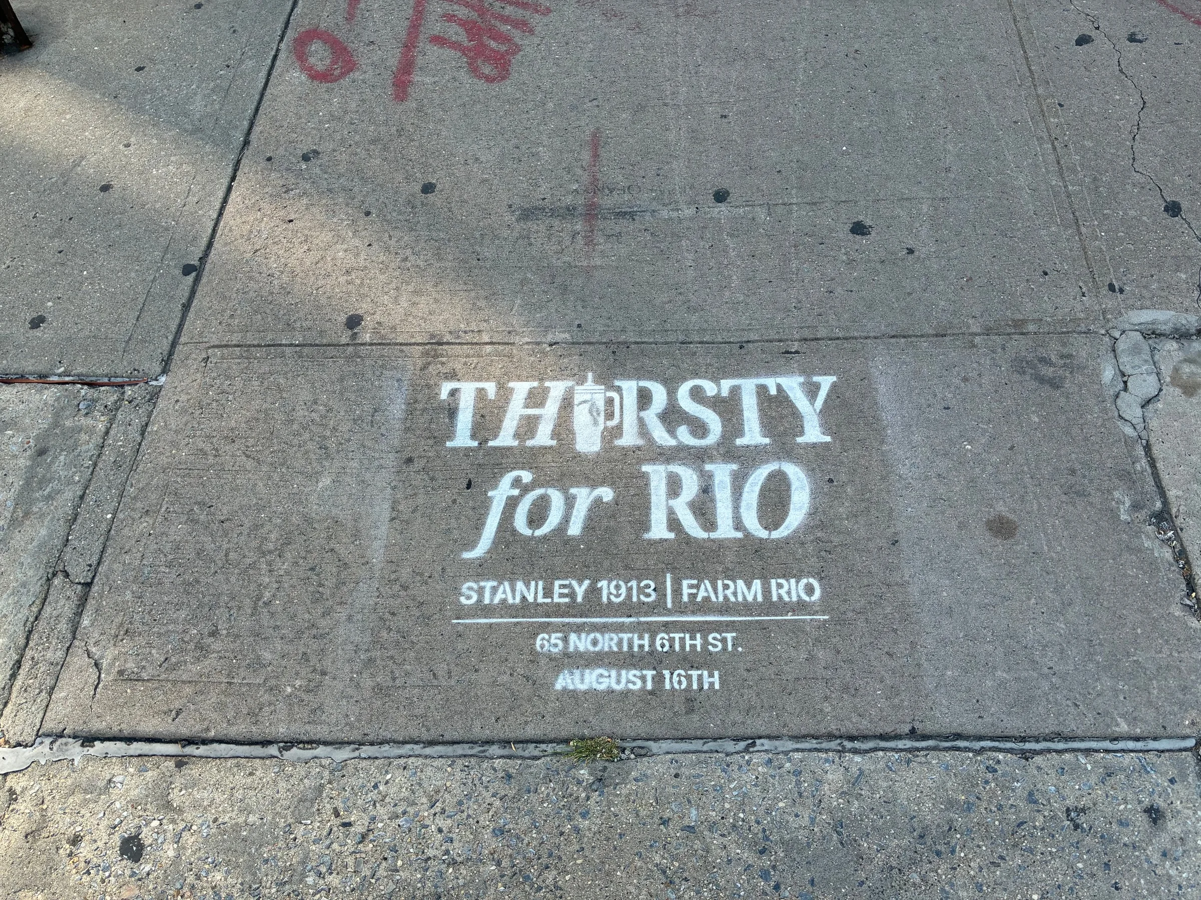 Stencil on a weathered Williamsburg slab with red utility markings alongside.