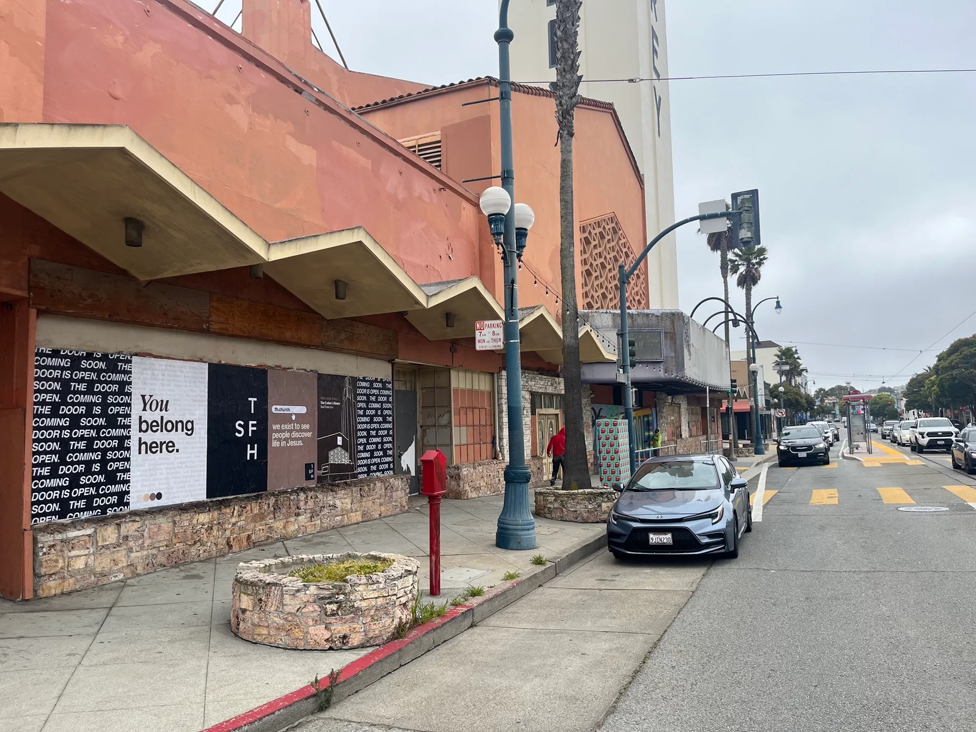 Jumbo custom-branded posters for The Father's House SF covering a street-level wall on Ocean Avenue in San Francisco, CA by Beyond Street Media