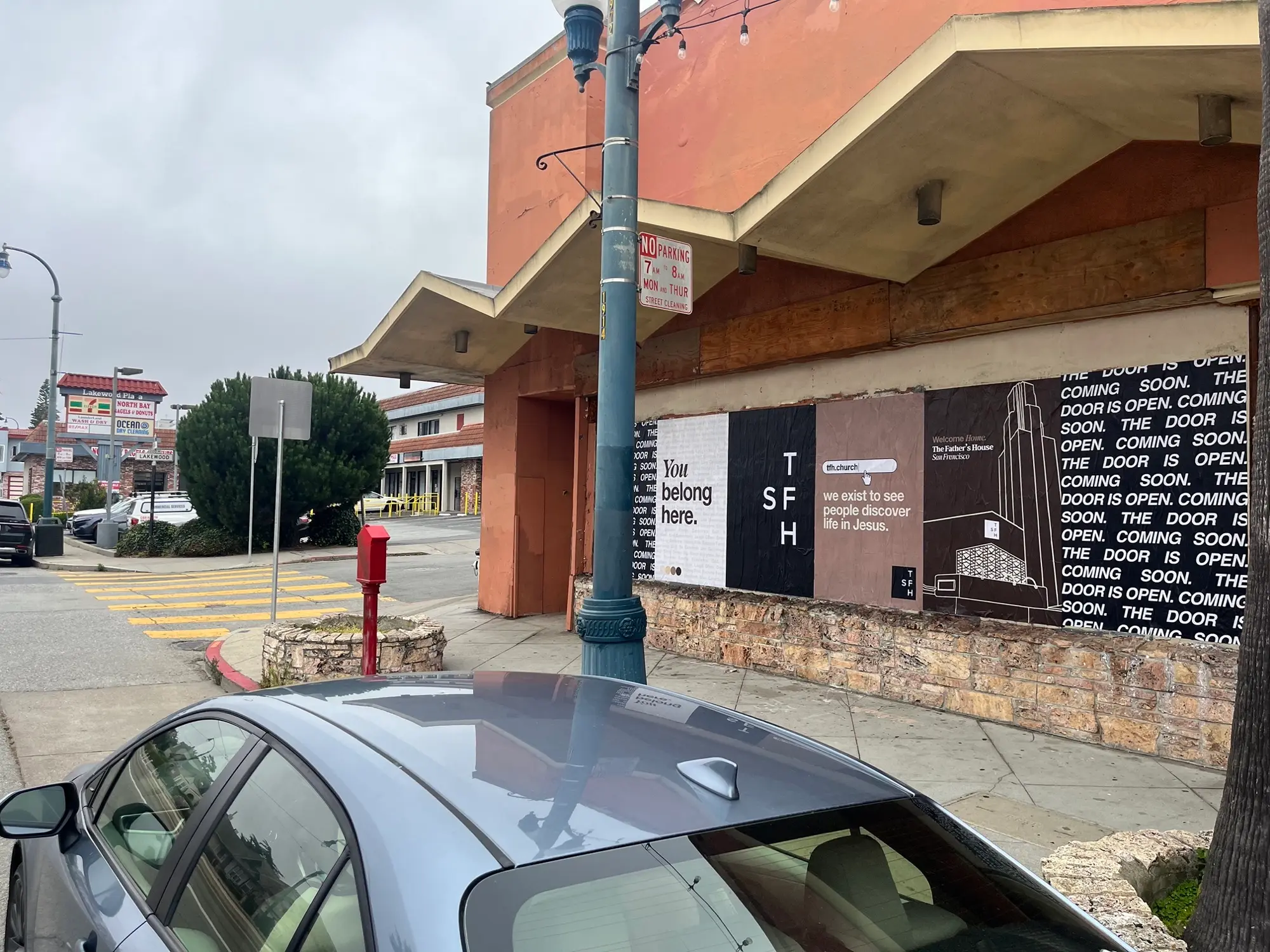 Jumbo custom-branded posters for The Father's House SF covering a street-level wall on Ocean Avenue in San Francisco, CA by Beyond Street Media