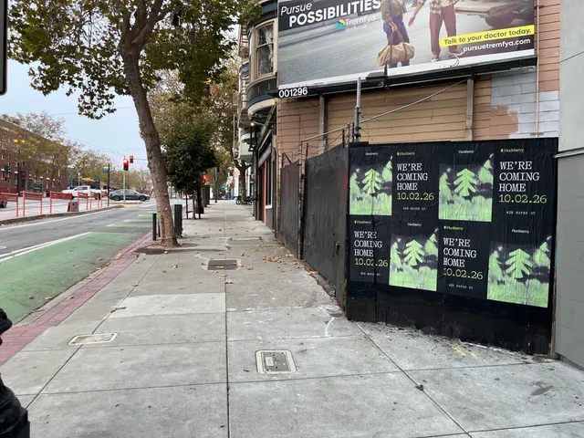 Huckberry wheatpaste posters on a black-painted fence on Market Street near Octavia, on the Mission side, the green Market Street bike lane alongside