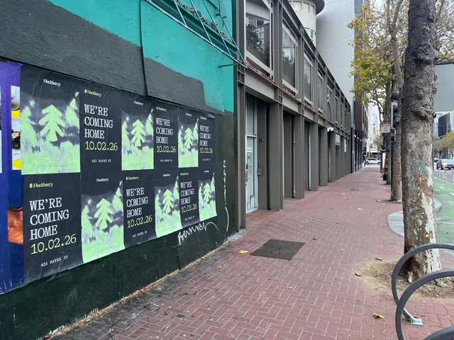 Huckberry wheatpaste posters gridded down a teal and black wall on Market Street between Gough and Octavia, brick sidewalk below