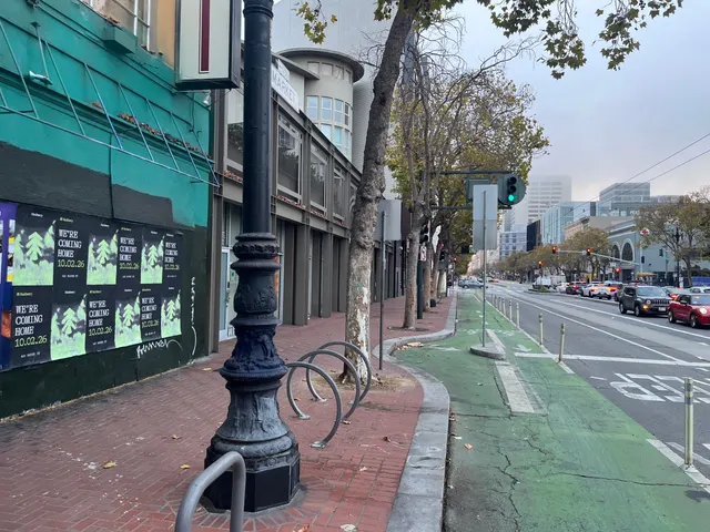 Huckberry wheatpaste posters on a teal and black wall on Market Street between Gough and Octavia, a lamppost and bike racks on the brick sidewalk
