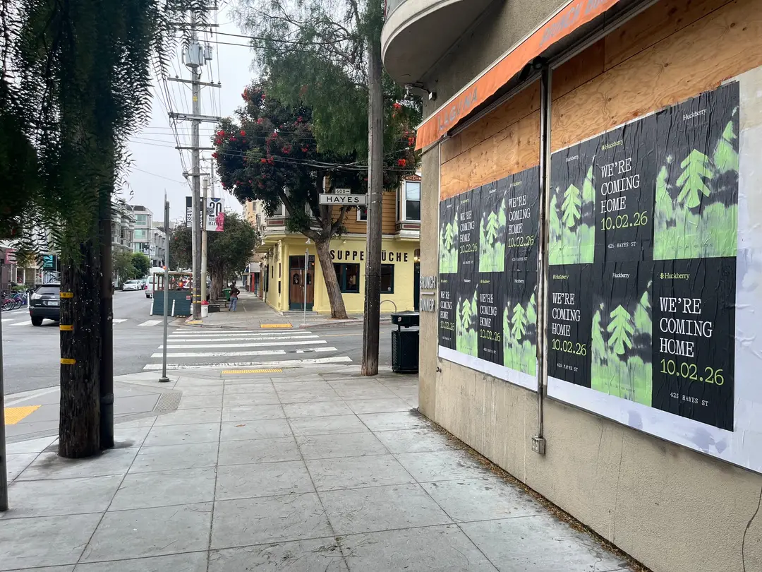 Huckberry wheatpaste posters on a boarded corner storefront at Hayes and Laguna, Hayes Valley, Suppenküche across the intersection
