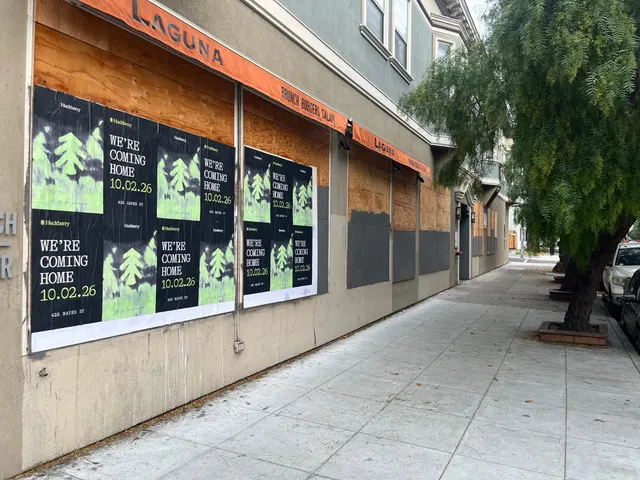 Huckberry wheatpaste posters in two blocks along a boarded storefront at Hayes and Laguna, Hayes Valley, looking down Laguna Street