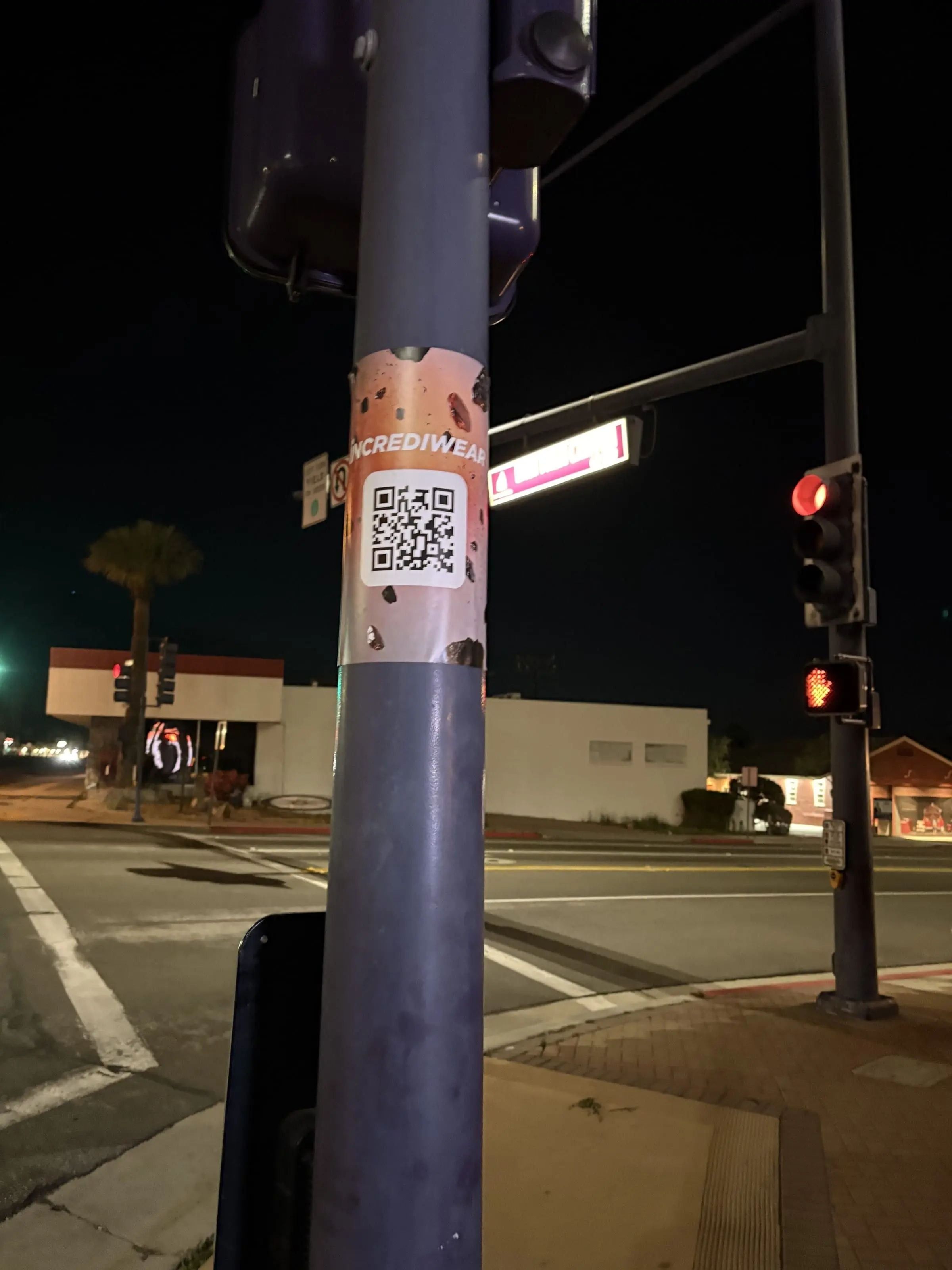 Incrediwear pull-tab QR pole sticker in the Coachella Valley during the BNP Paribas Open, documented street install, by Beyond Street Media