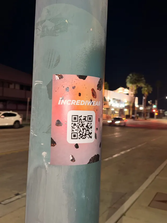 Incrediwear pull-tab QR pole sticker in the Coachella Valley during the BNP Paribas Open, documented street install, by Beyond Street Media (photo 19 of 38).