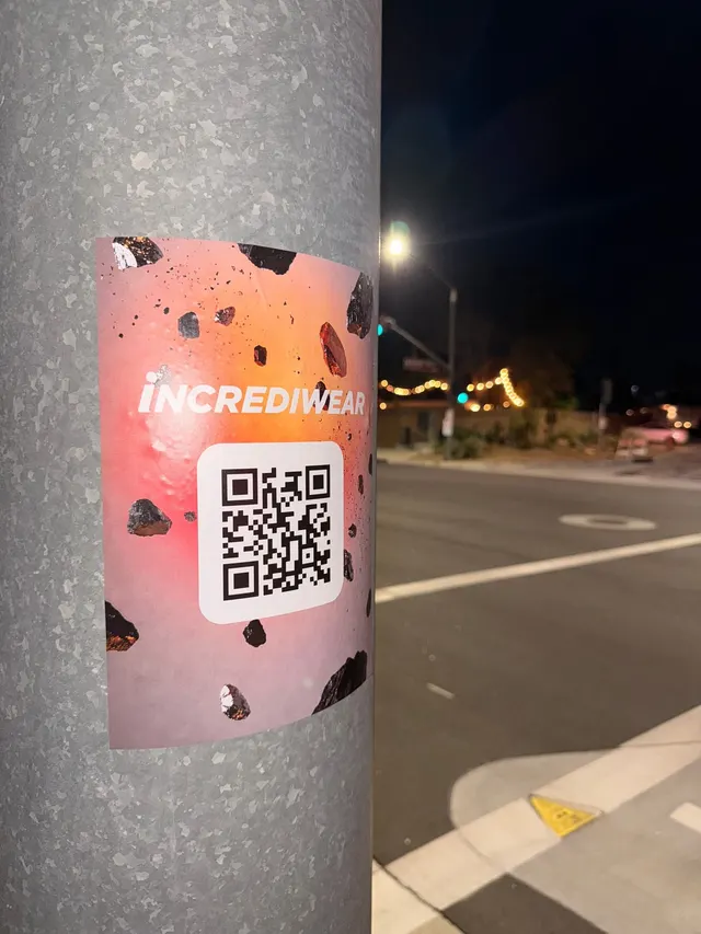 Incrediwear pull-tab QR pole sticker in the Coachella Valley during the BNP Paribas Open, documented street install, by Beyond Street Media (photo 20 of 38).