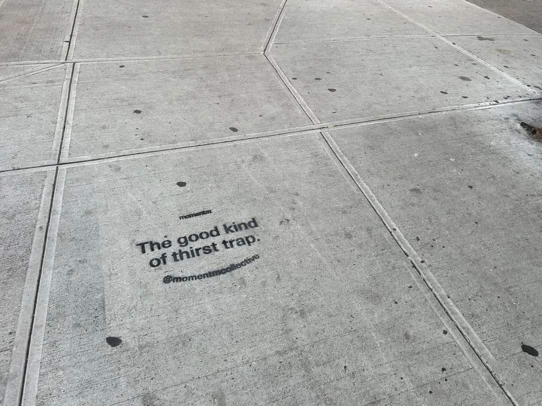Frontal Momentm sidewalk stencil, one of three approved designs, on New York concrete.