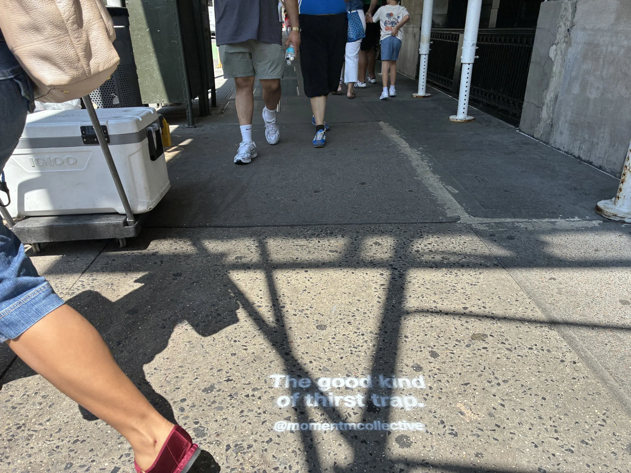 Foot traffic stepping past a Momentm sidewalk stencil in New York.