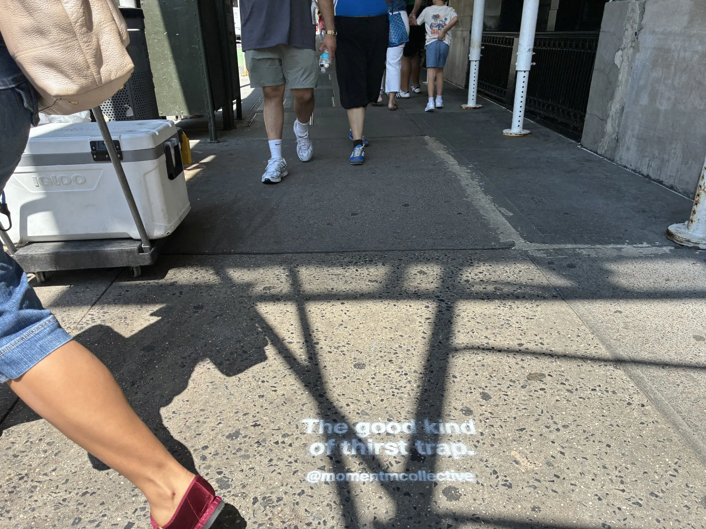 Foot traffic stepping past a Momentm sidewalk stencil in New York.