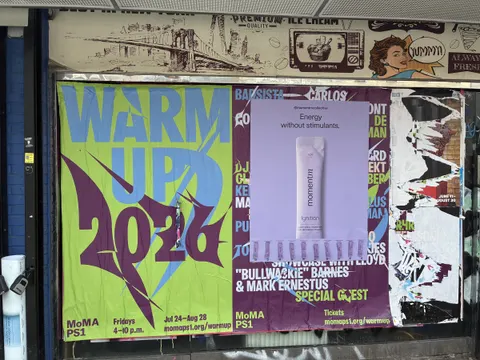 Momentm takeaway poster in lavender with sample stick packs pasted into a South Williamsburg poster wall.