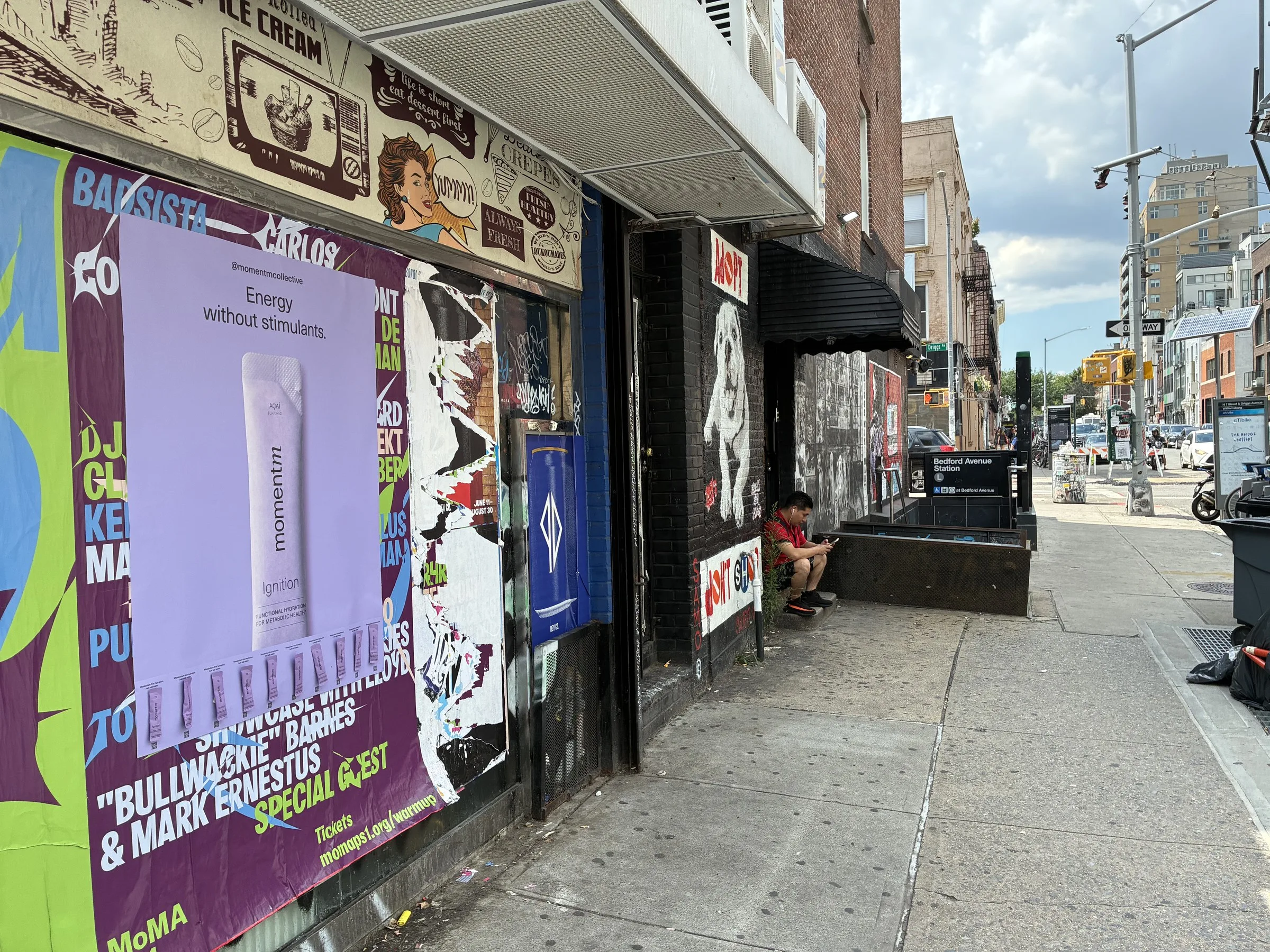 Street view of the lavender Momentm takeaway poster with samples, storefronts beyond.