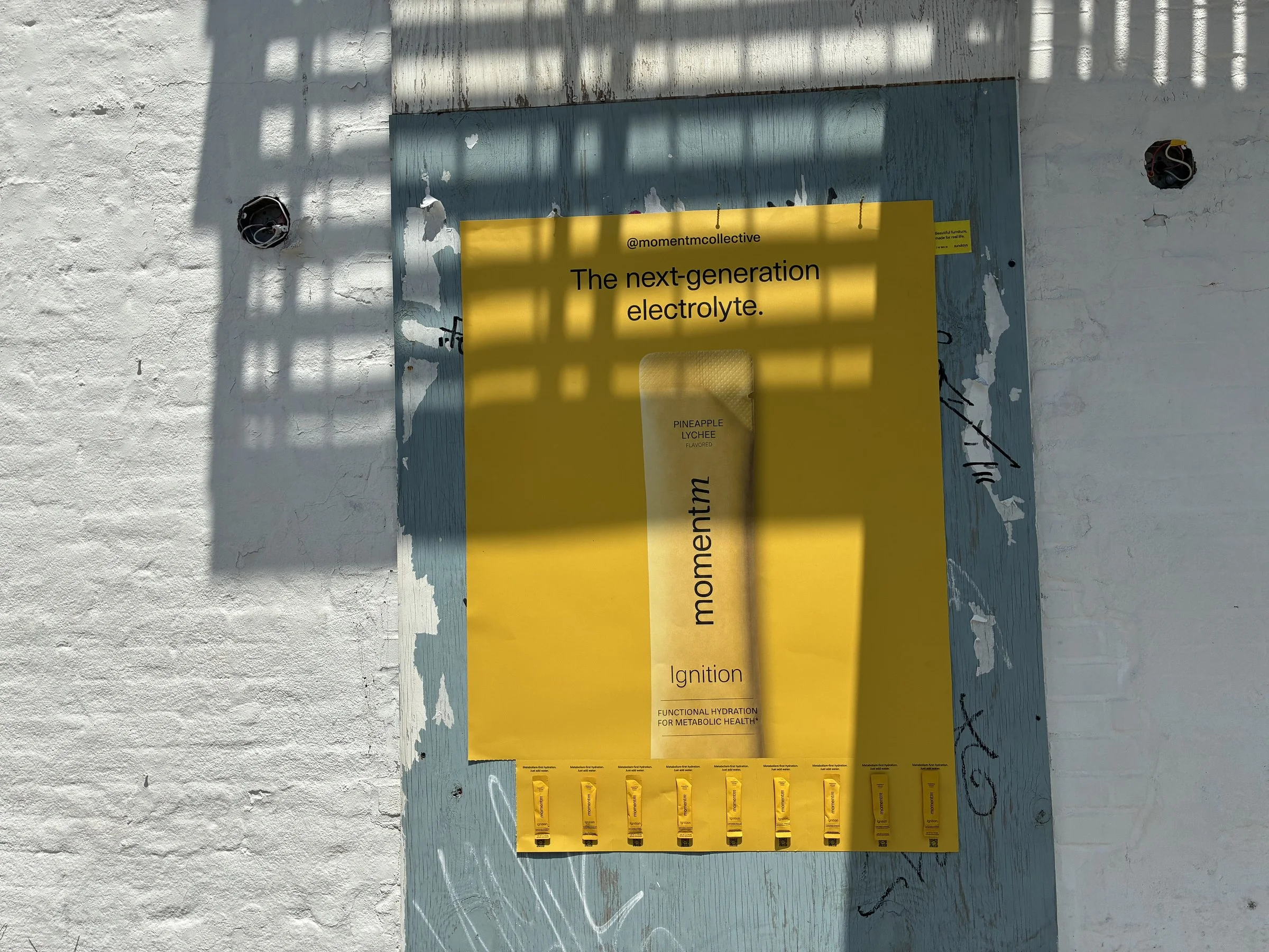 Momentm takeaway poster with product sample stick packs installed on a New York wall by Beyond Street Media.