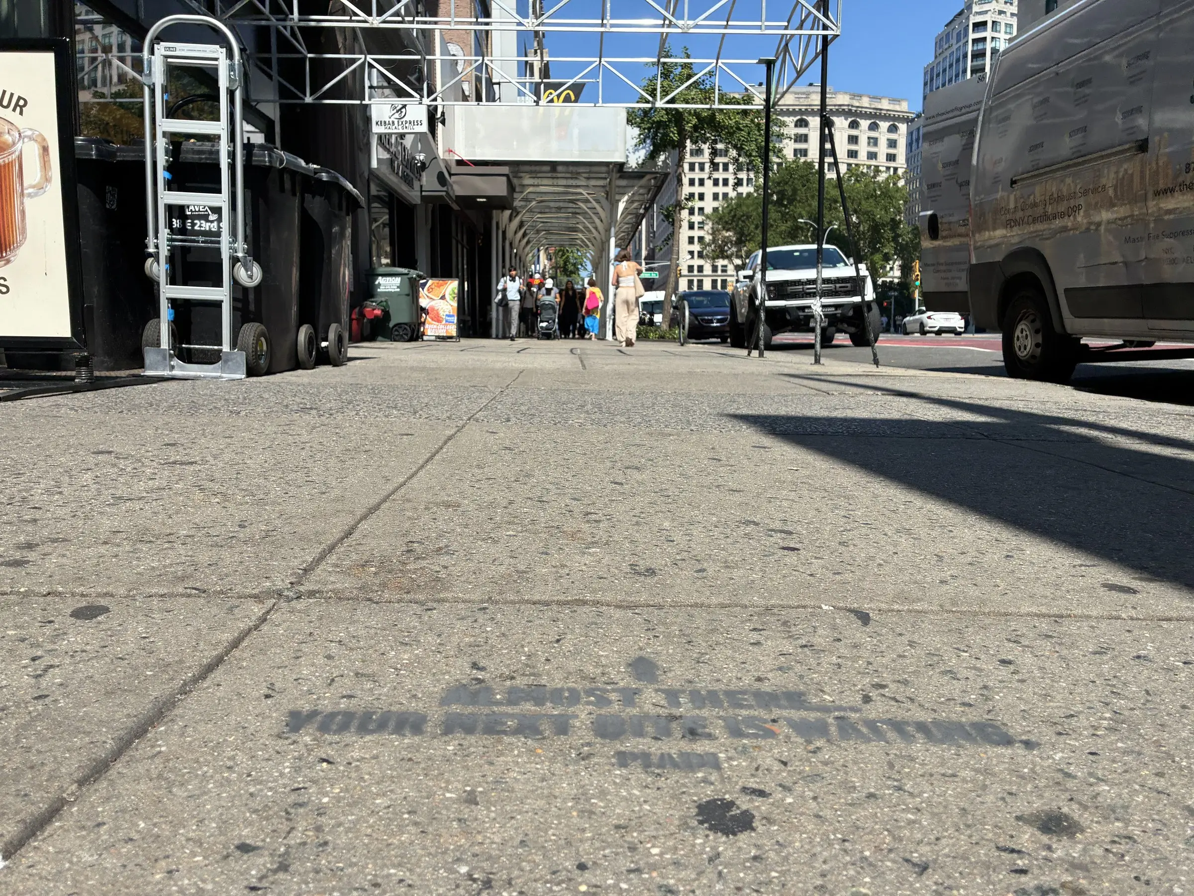 PIADI wayfinding chalk stencil mid-block between the subway entrance and the store.