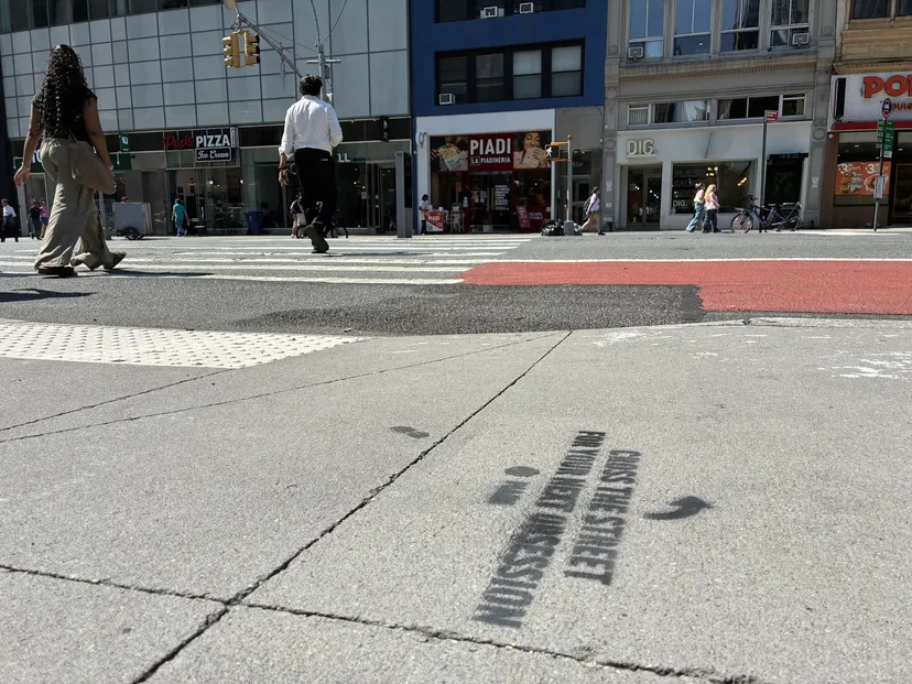 Directional arrow chalk stencils leading foot traffic across toward the PIADI storefront.