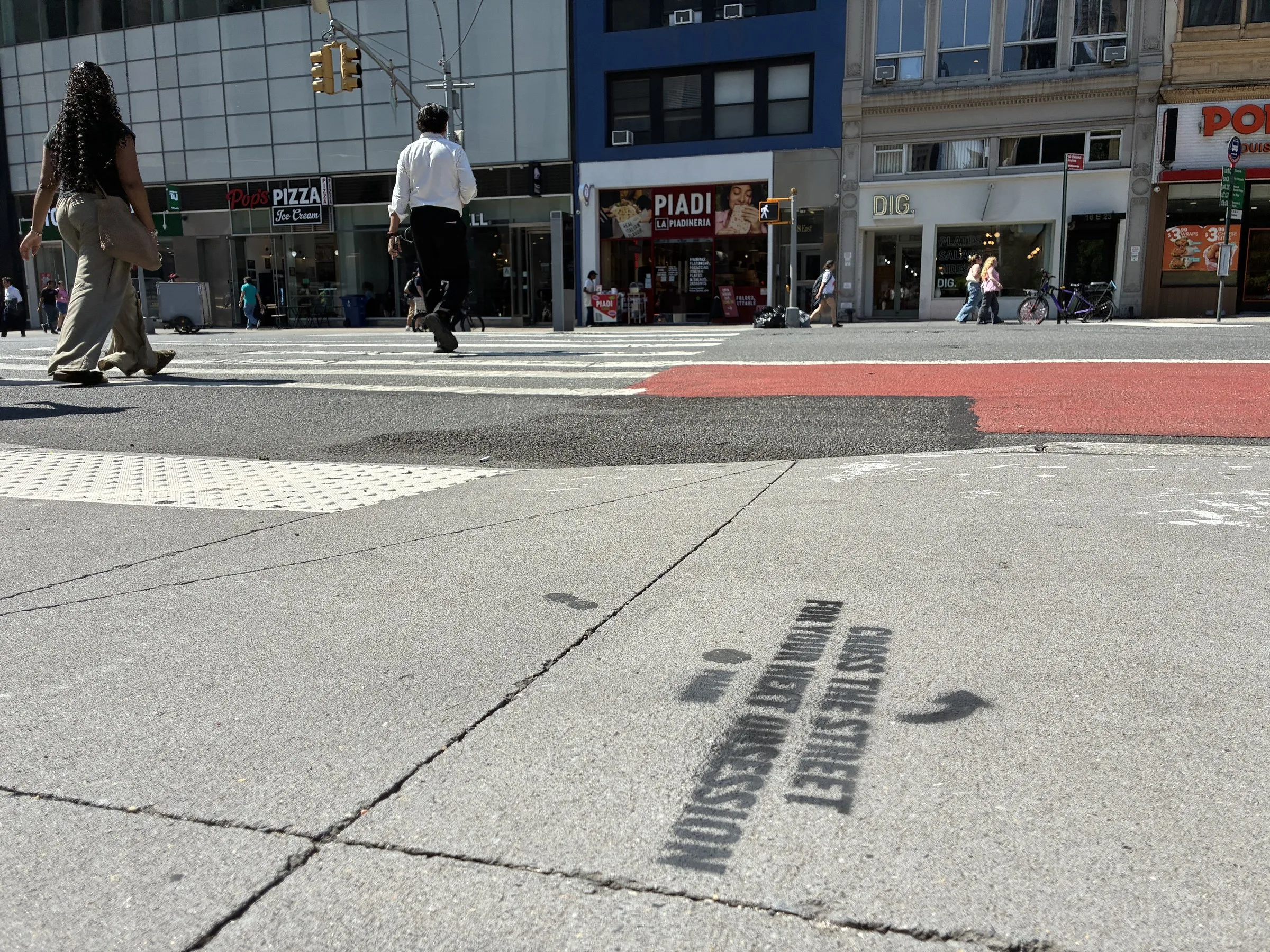 Directional arrow chalk stencils leading foot traffic across toward the PIADI storefront.