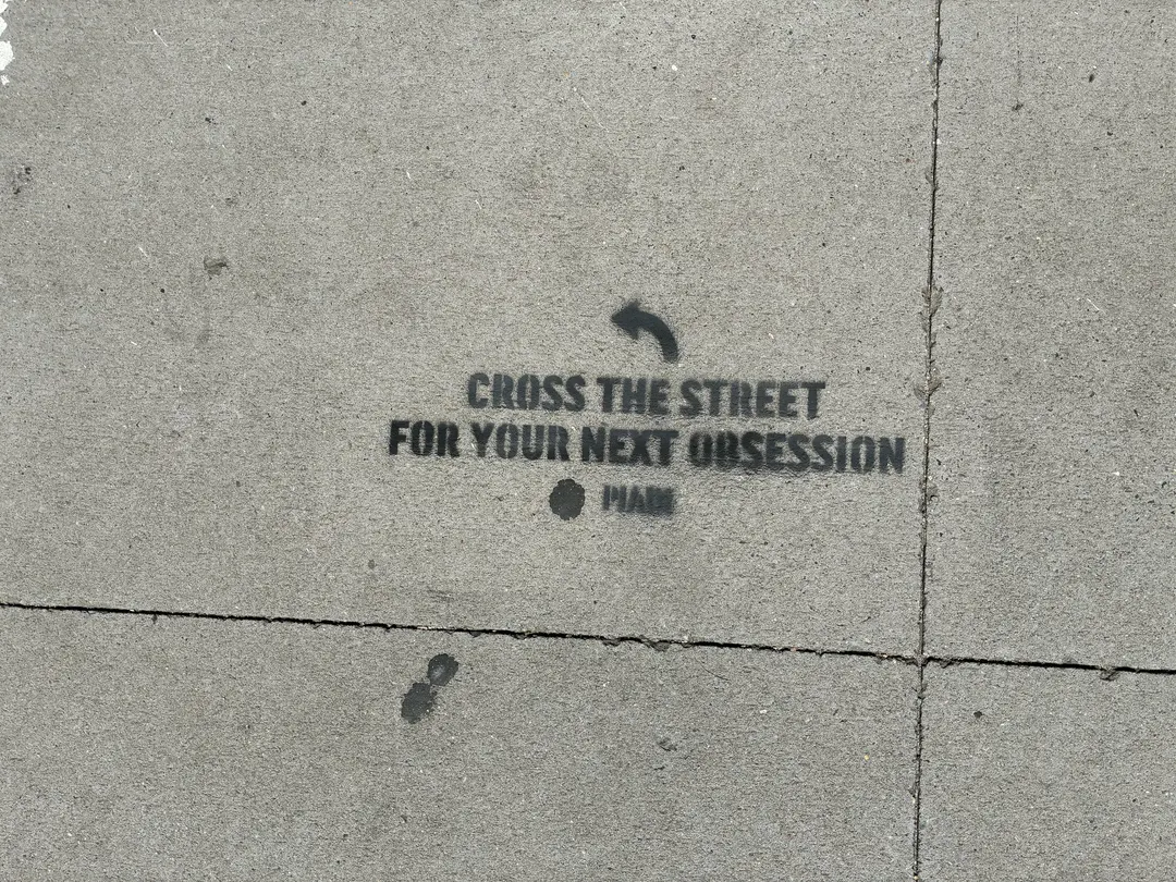 PIADI chalk stencil reading Cross the street for your next obsession, placed on the IBM side of the block.