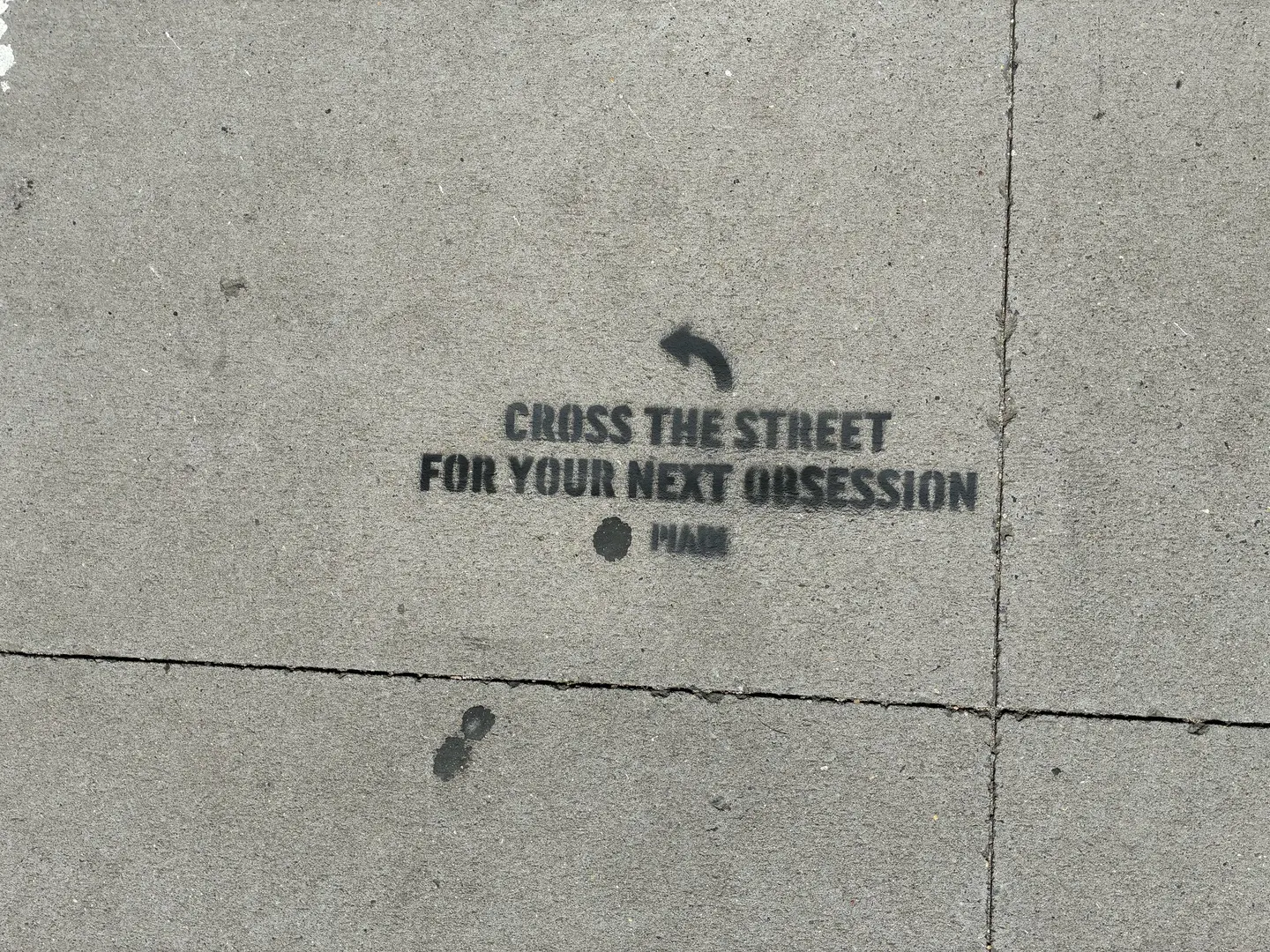 PIADI chalk stencil reading Cross the street for your next obsession, placed on the IBM side of the block.