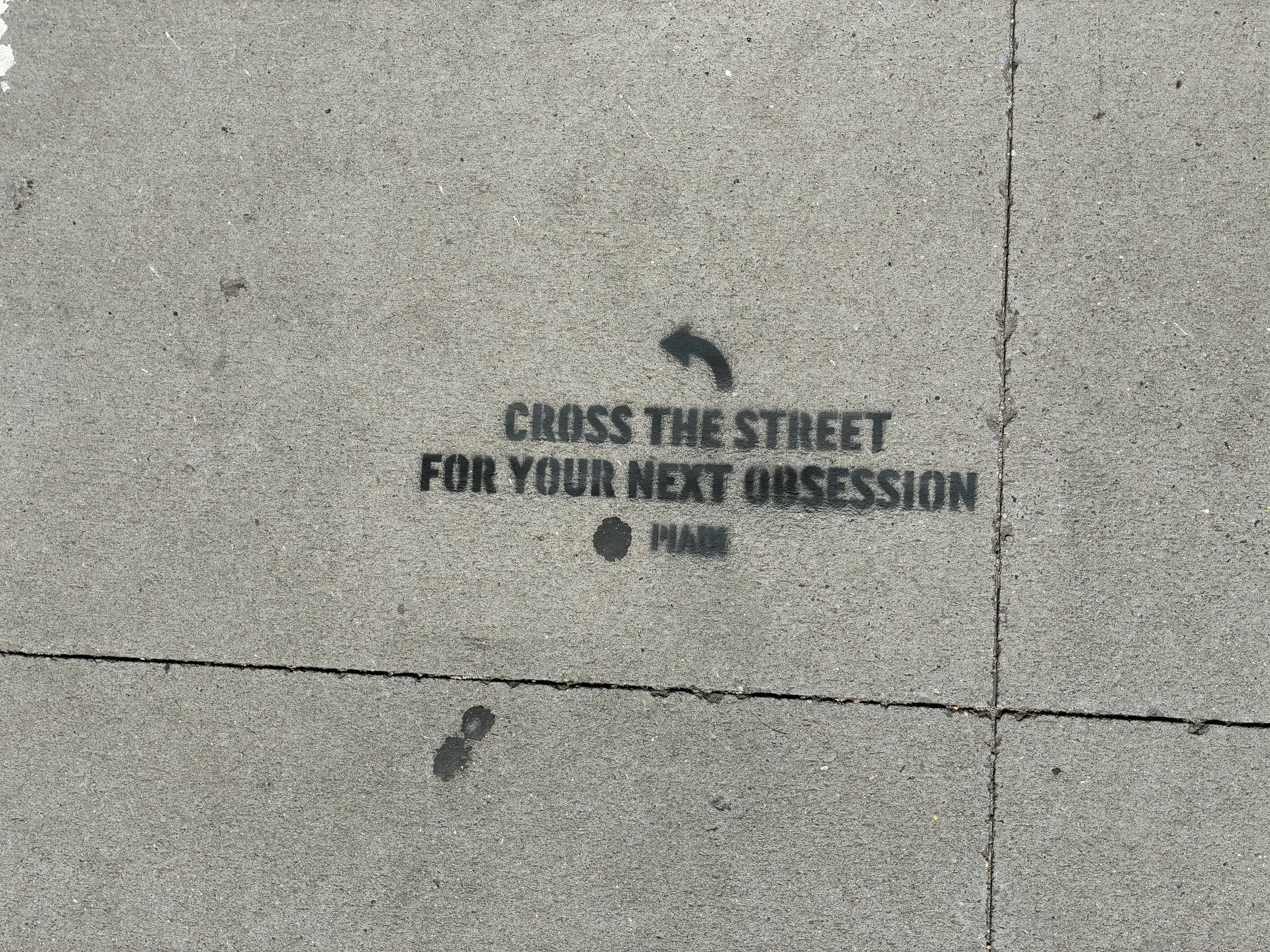 PIADI chalk stencil reading Cross the street for your next obsession, placed on the IBM side of the block.