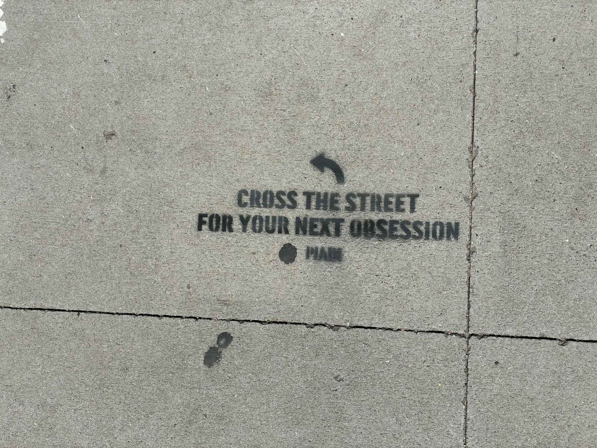 PIADI chalk stencil reading Cross the street for your next obsession, placed on the IBM side of the block.