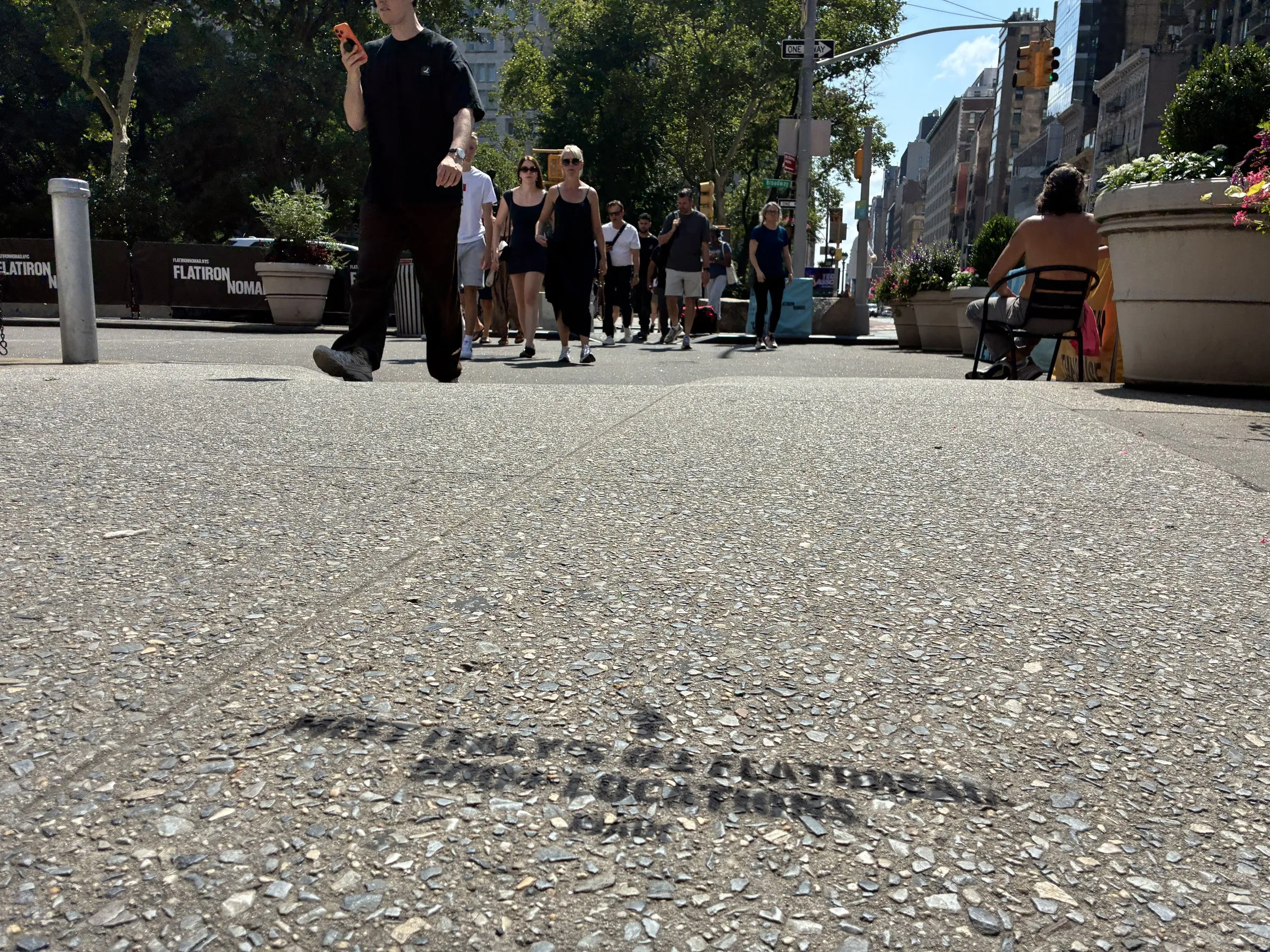 PIADI chalk stencil on the north side of 23rd St and Broadway with pedestrians beyond.