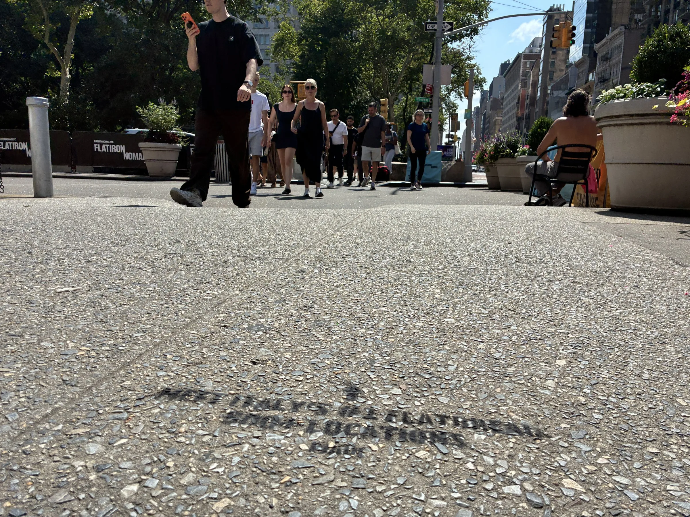 PIADI chalk stencil on the north side of 23rd St and Broadway with pedestrians beyond.