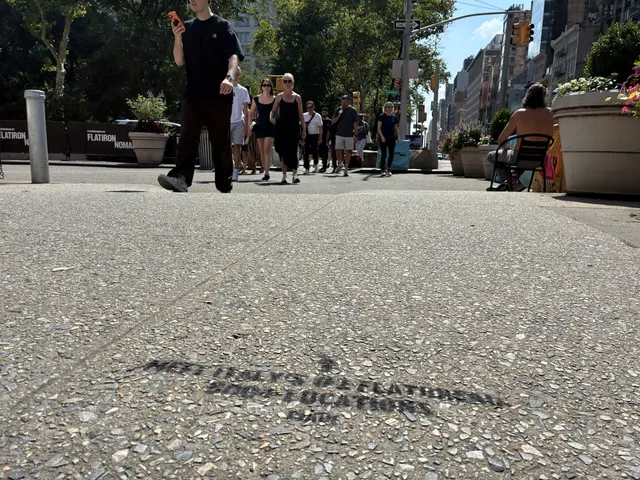PIADI chalk stencil on the north side of 23rd St and Broadway with pedestrians beyond.