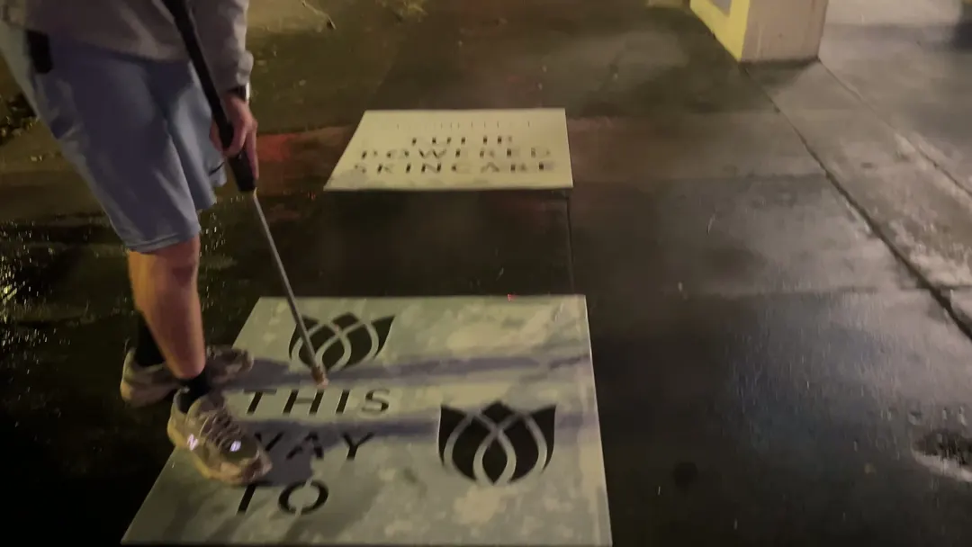 Reverse stencil clean-tag install for Bloomeffects 'Tulip Powered Skincare' on New York City sidewalk in New York City: pressure-washed logo revealed in clean concrete by Beyond Street Media. No paint, no chalk, no ink, only the absence of grime (photo 4 of 4).