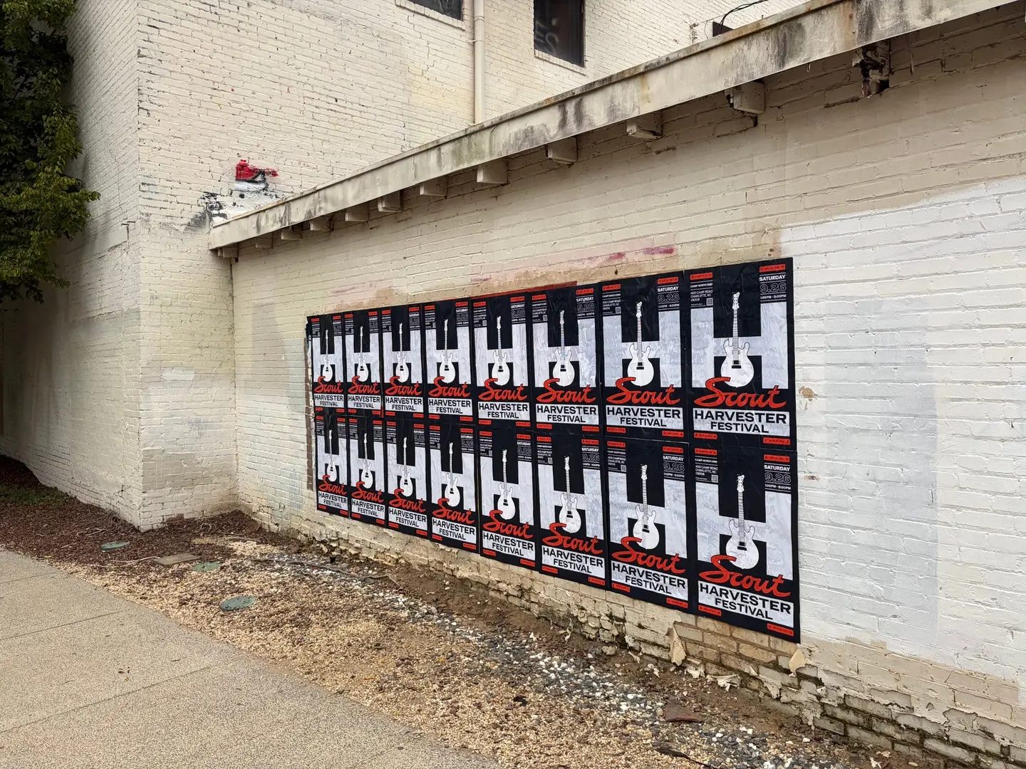 Scout Harvester wheatpaste in the dark colorway on a chipped white brick wall at Charlotte Rail Trail, South End, sixteen sheets