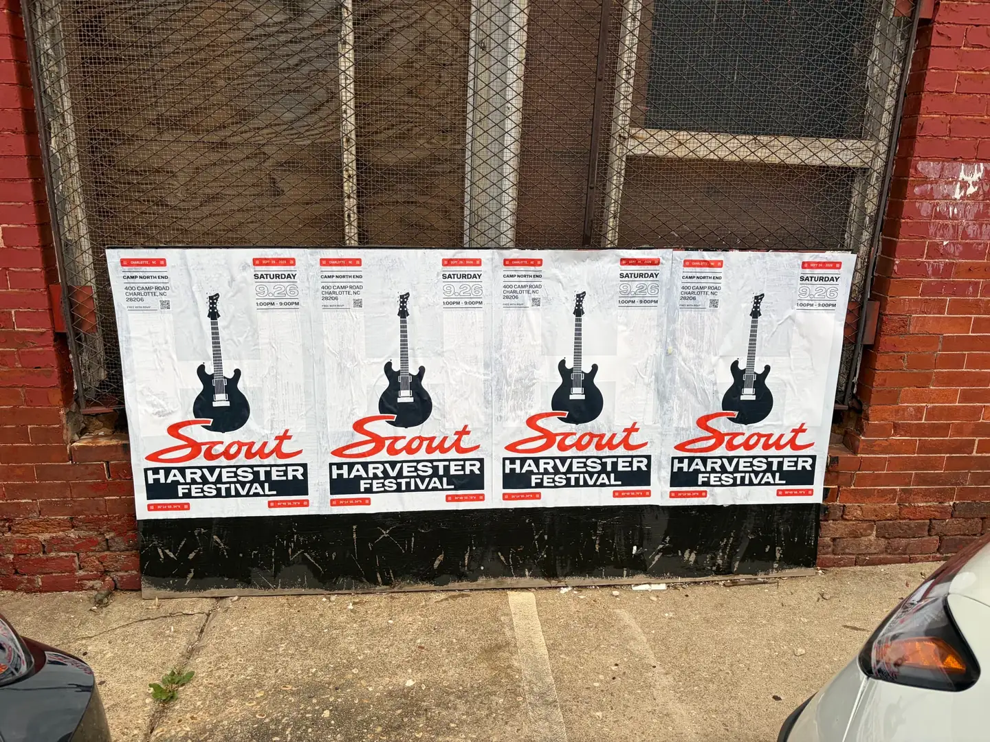 Scout Harvester wheatpaste in the white and silver colorway on a mesh security gate at North Brevard Street, a van parked alongside