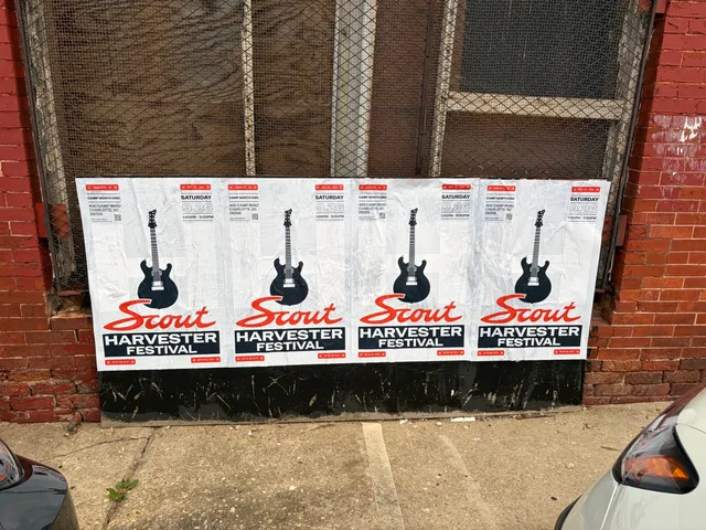 Scout Harvester wheatpaste in the white and silver colorway on a mesh security gate at North Brevard Street, a van parked alongside