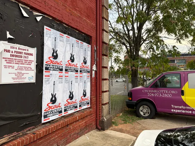 Scout Harvester wheatpaste in the white and silver colorway on red brick at North Brevard Street, beside a parking contract sign