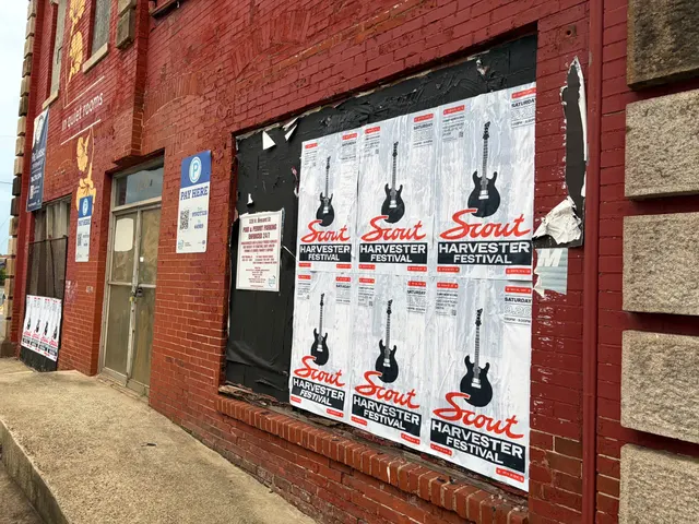 Scout Harvester wheatpaste in the white and silver colorway on red brick at North Brevard Street, beside a Pay Here meter sign