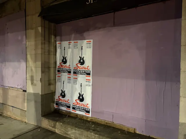 Scout Harvester wheatpaste in the white and silver colorway on a lavender wall at West Trade Street, Gateway, under an awning at night