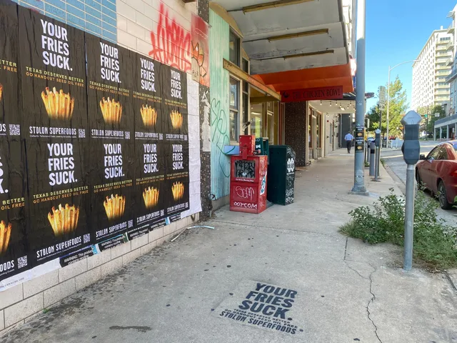 Stolon Superfoods wheatpaste posters, two stacked pole stickers and a black chalk stencil in one frame on Lavaca Street, in daylight