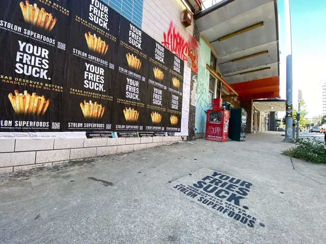 Stolon Superfoods chalk stencil in black on the sidewalk in front of the YOUR FRIES SUCK. poster run on Lavaca Street, in daylight