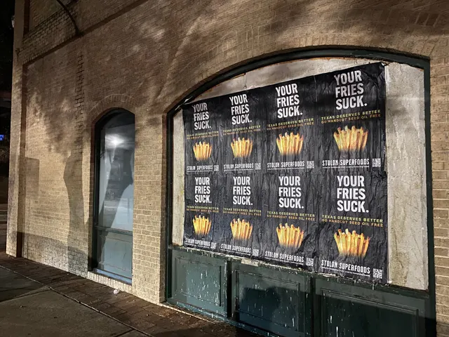 Stolon Superfoods wheatpaste posters, eight in two rows of four, filling a boarded arched window on East 6th Street, downtown, at night