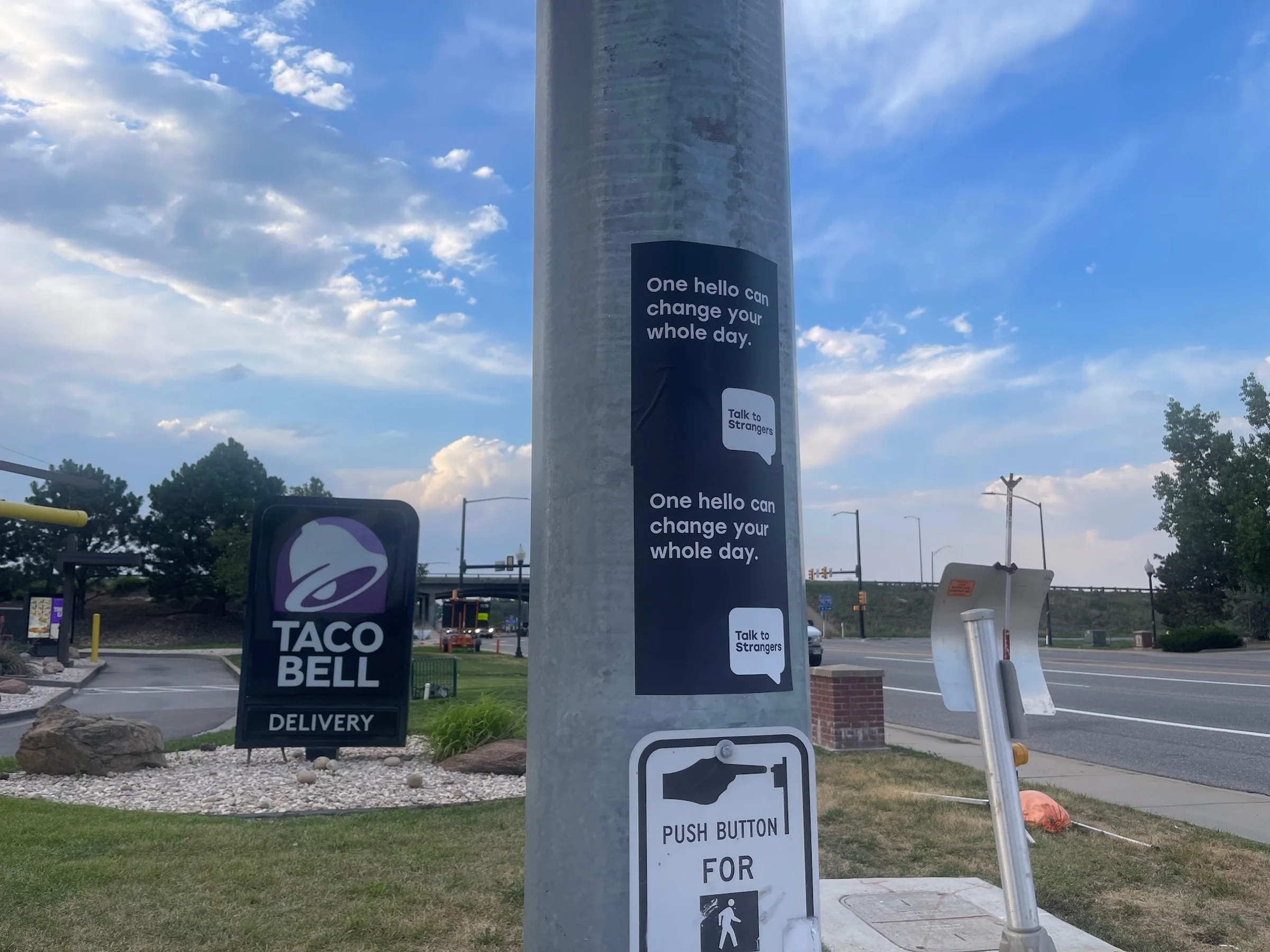 Talk to Strangers pole sticker install by Beyond Street Media at 4775 Kipling St, Wheat Ridge, Colorado — a 'One hello can change your whole day.' pole sticker on a commercial corridor.