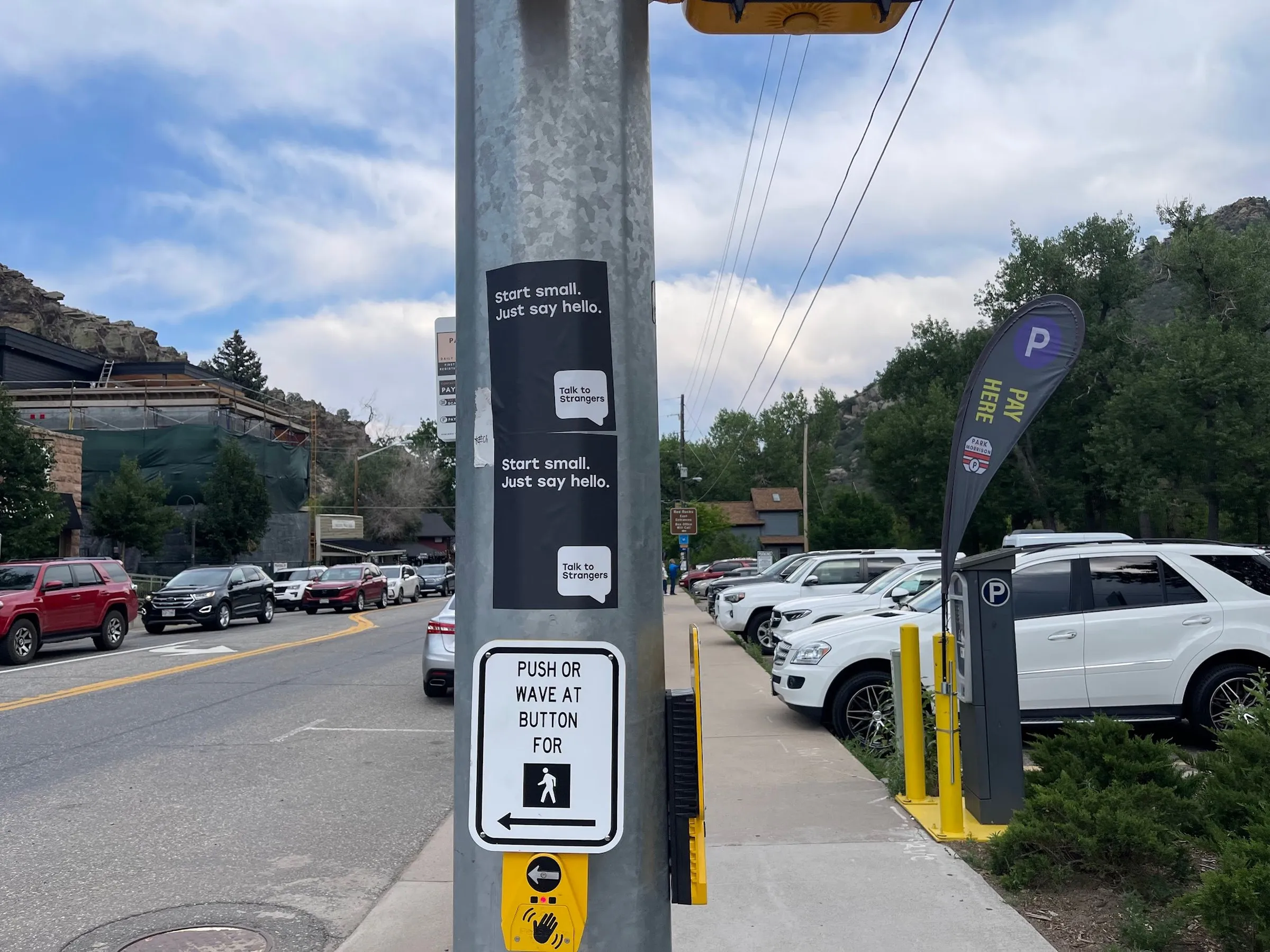 Talk to Strangers pole sticker install by Beyond Street Media at Tony Rigatoni's Italian Kitchen, Morrison, Colorado — a pole sticker in a restaurant parking lot with the foothills behind.