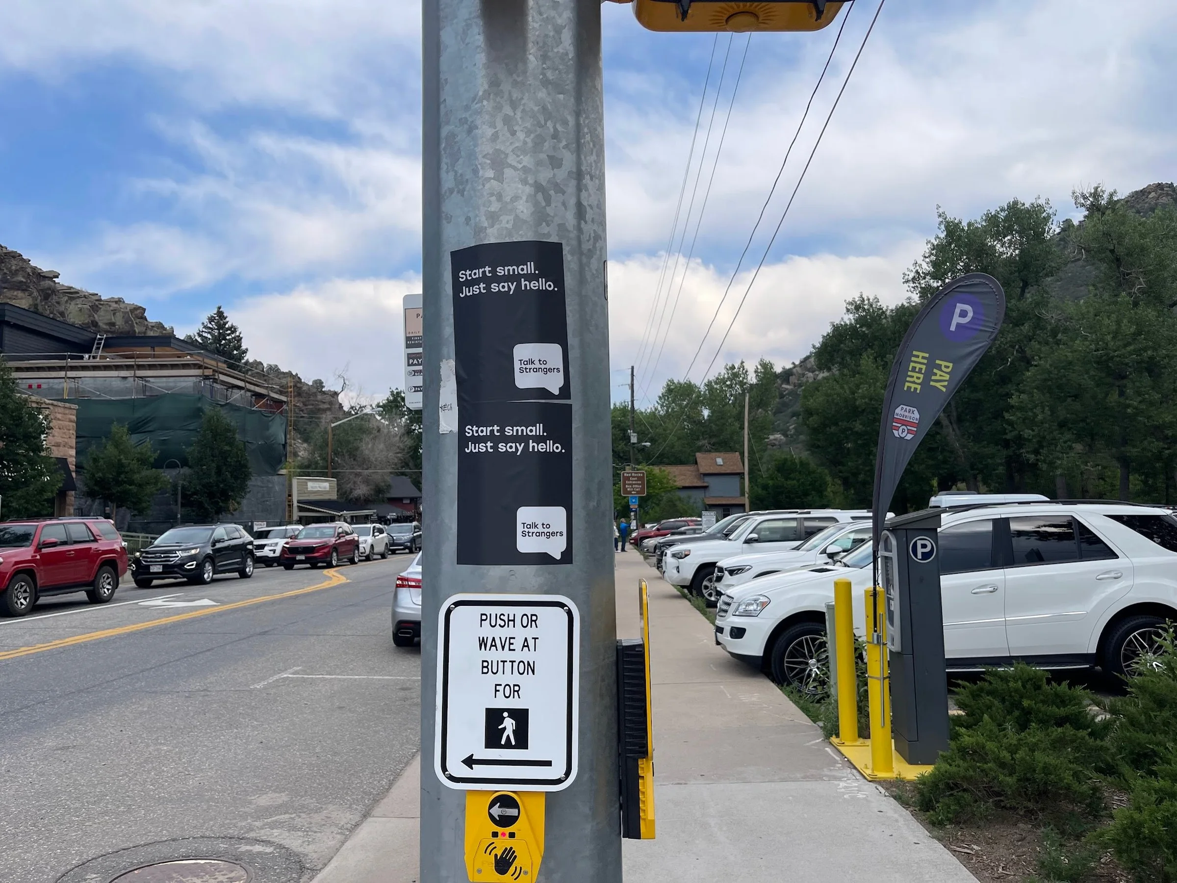 Talk to Strangers pole sticker install by Beyond Street Media at Tony Rigatoni's Italian Kitchen, Morrison, Colorado — a pole sticker in a restaurant parking lot with the foothills behind.