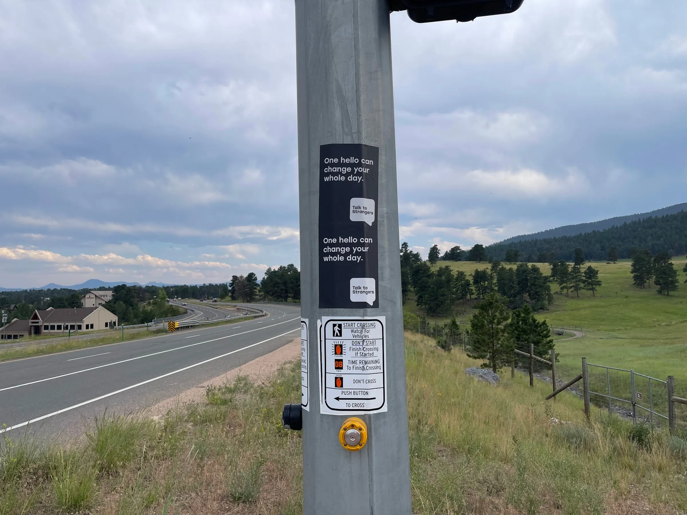 Talk to Strangers pole sticker install by Beyond Street Media at 32114 Ellingwood Trail, Evergreen, Colorado — a pole sticker on a highway-side pole in the foothills.