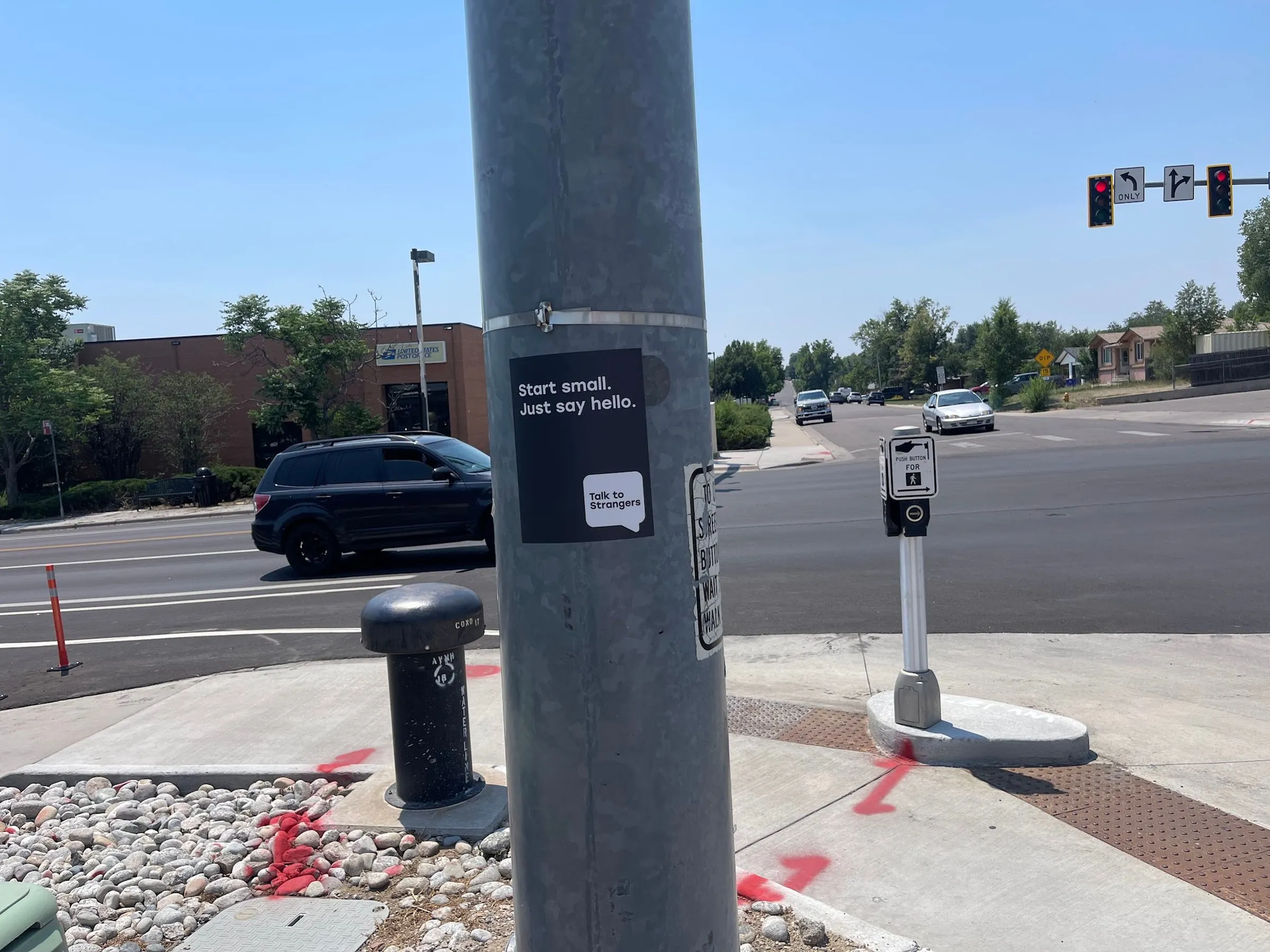 Talk to Strangers pole sticker install by Beyond Street Media at 5507 W 20th Ave, Edgewater, Colorado — a pole sticker at a pedestrian signal on a main avenue.