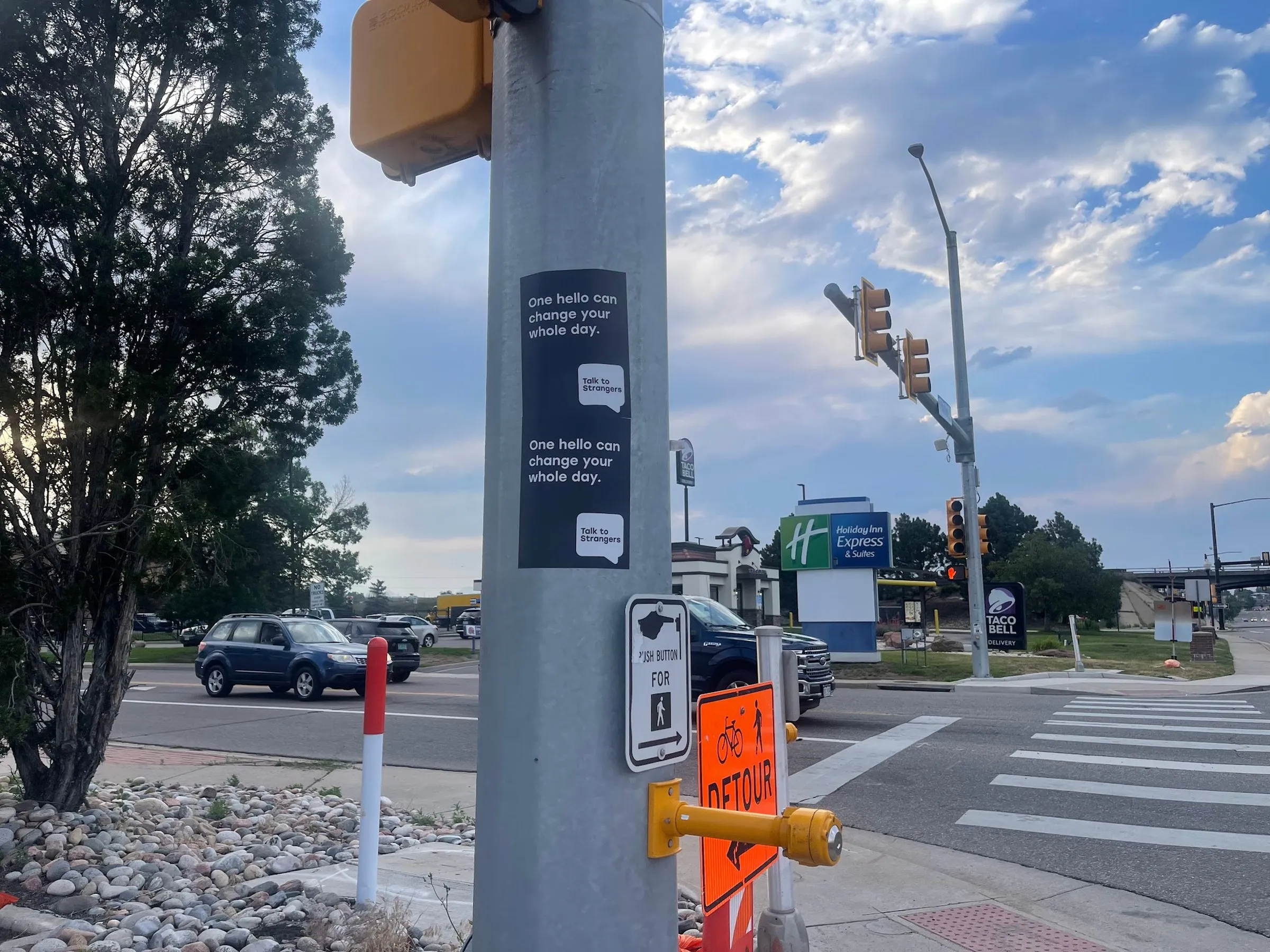 Talk to Strangers pole sticker install by Beyond Street Media at 4775 Kipling St, Wheat Ridge, Colorado — a pole sticker on a signal pole at a retail crossroads.