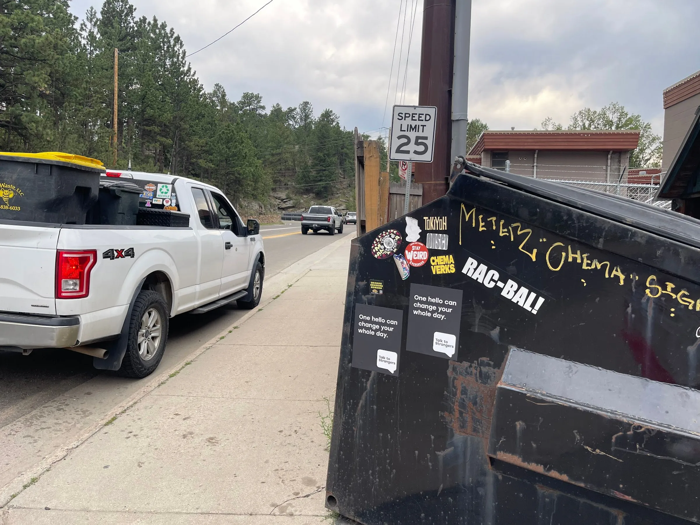 Talk to Strangers pole sticker install by Beyond Street Media at 4651 County Hwy 73, Evergreen, Colorado — a sticker placed among existing stickers on a roadside fixture.