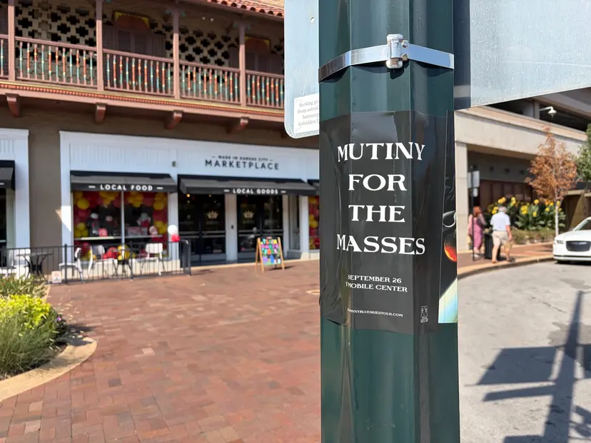 Mutiny for the Masses pole snipe at Country Club Plaza, Made in Kansas City Marketplace storefront and brick pavers behind it