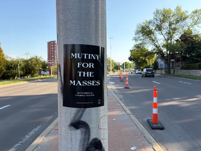 Mutiny for the Masses pole snipe at Mill Street, Westport, orange traffic cones lining the street toward a red high-rise building